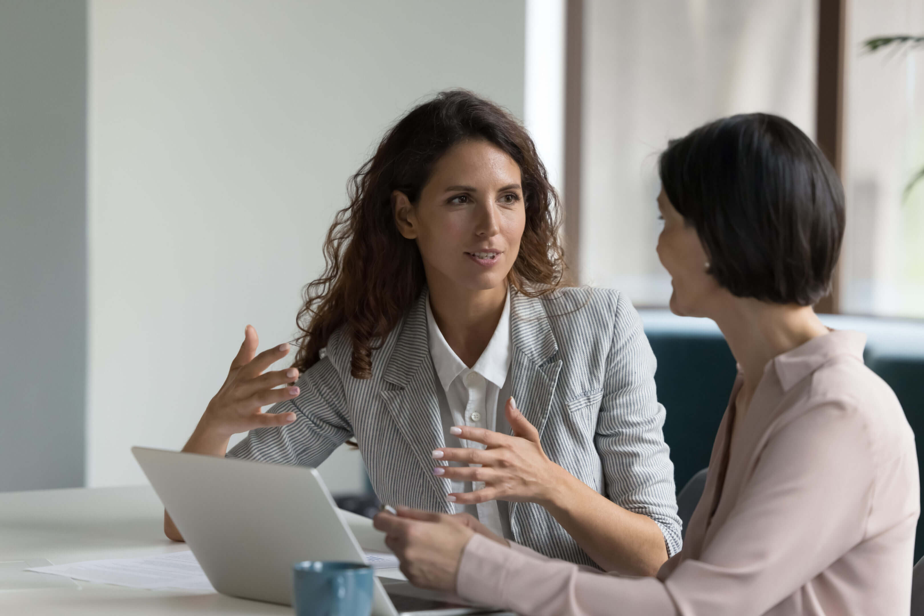 Two women engaged in a serious business discussion in an office.