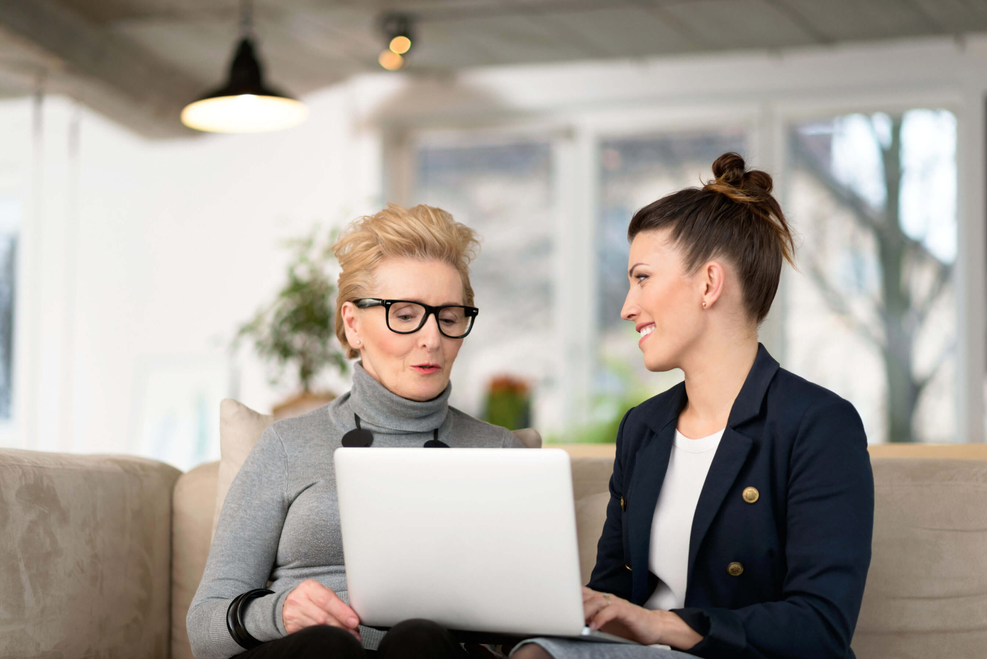 Two professional women discussing a laptop screen in an office.
