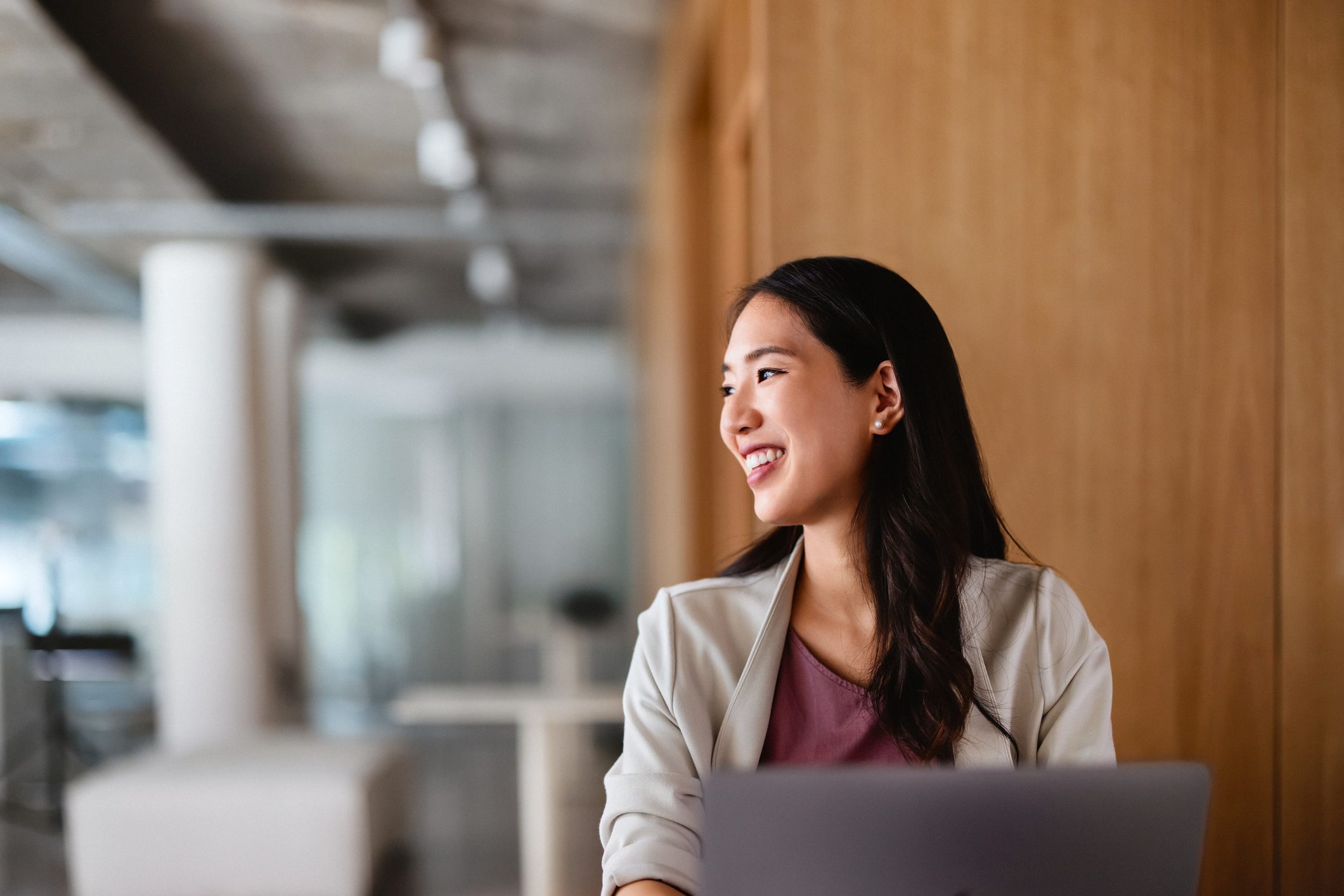 A woman smiling while looking to the side in a modern office.