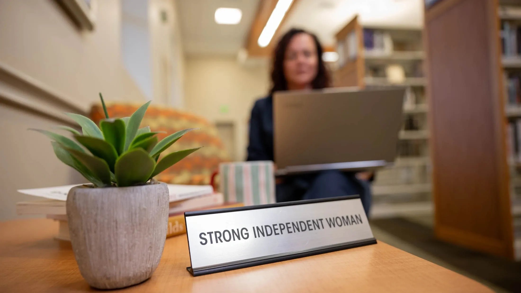 Sign Strong Independent Woman beside laptop user.